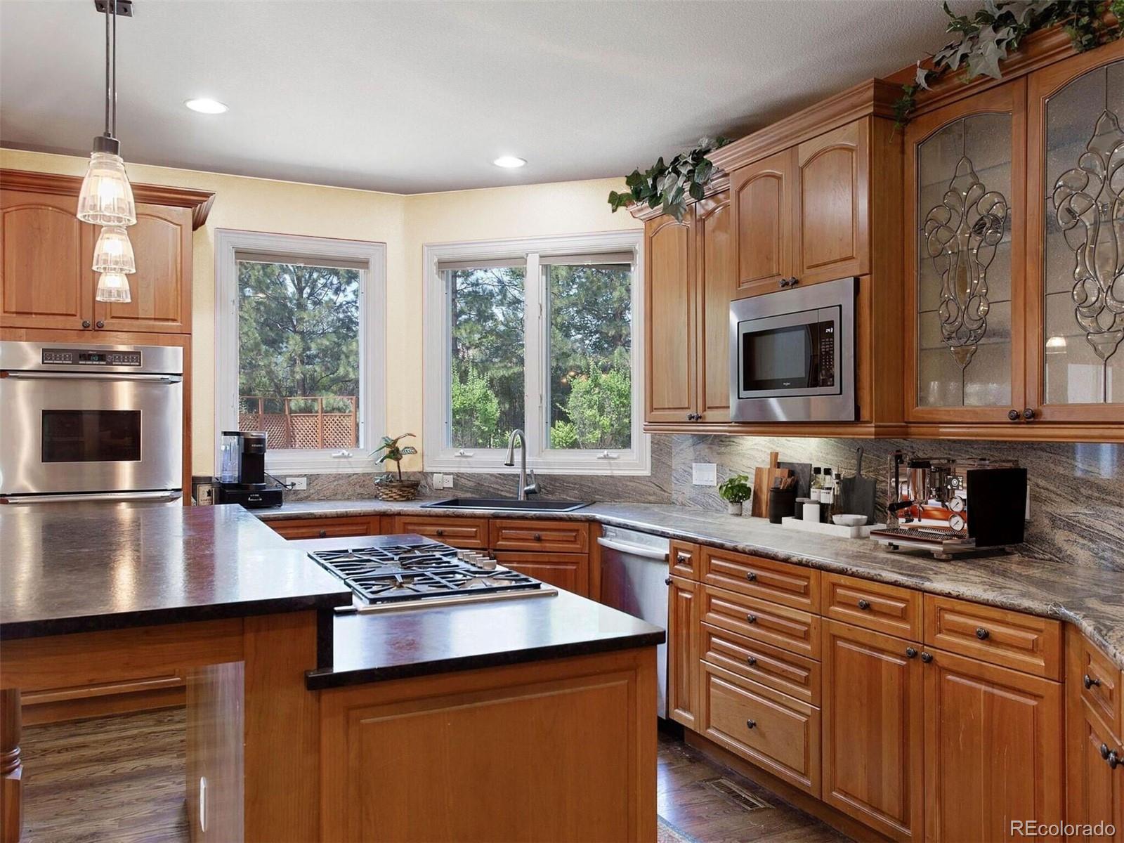 7125 Polo Ridge Drive Littleton, CO 80128 - Photo 11 of 25 a kitchen with stainless steel appliances a stove sink microwave and cabinets