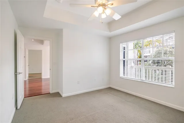an empty room with chandelier fan and windows