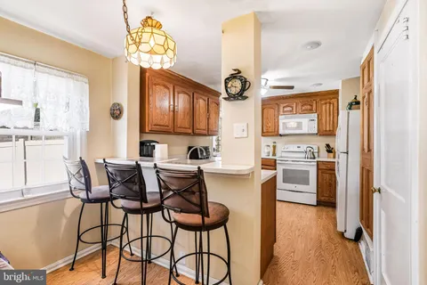 a kitchen with stainless steel appliances granite countertop a refrigerator a sink dishwasher a stove and a dining table with wooden floor