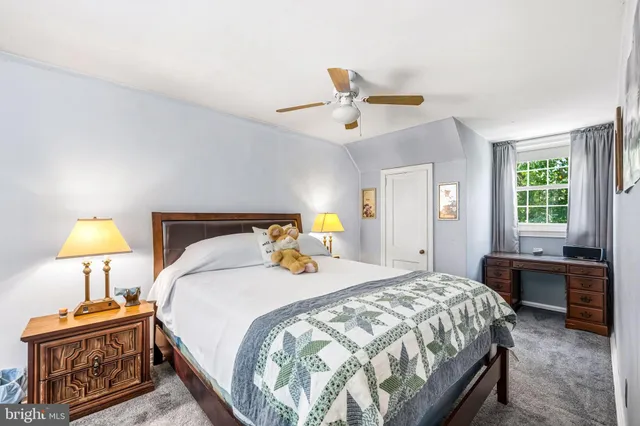 a bedroom with a bed a dresser and a potted plant