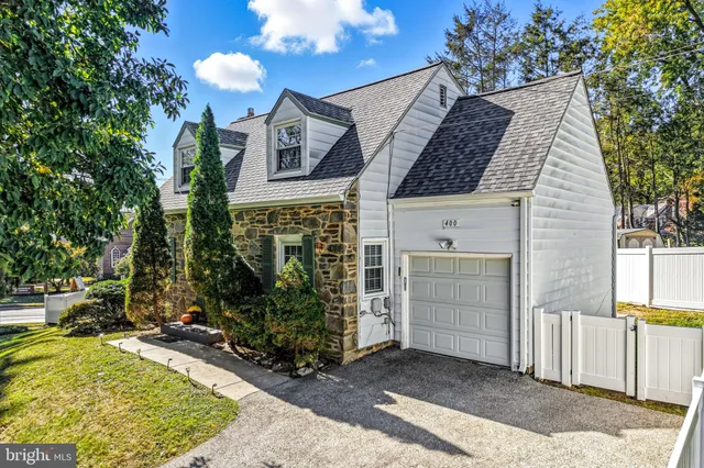 a view of a white house next to a yard with plants and trees