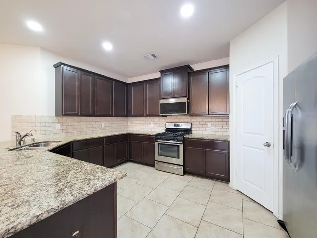 a kitchen with stainless steel appliances granite countertop a refrigerator and a sink