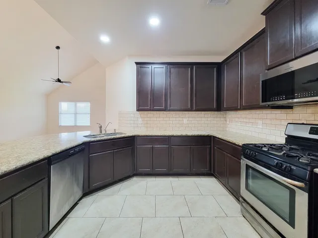 a kitchen with stainless steel appliances granite countertop wooden cabinets a stove top oven a sink and dishwasher