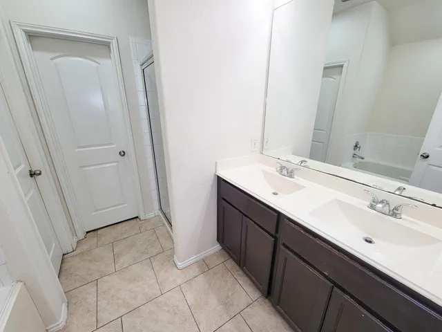 a spacious bathroom with a double vanity sink and mirror
