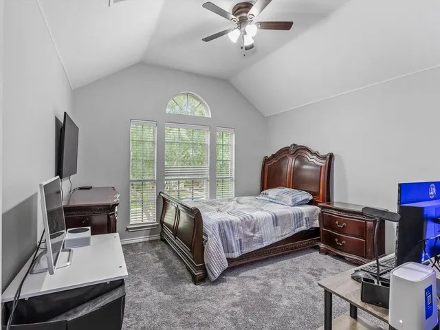 a bedroom with a bed a computer on the desk and a dresser
