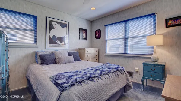 a bedroom with a bed and a lamp on dresser