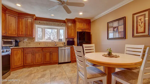 a kitchen with stainless steel appliances granite countertop a stove a sink dishwasher a dining table and chairs with wooden floor