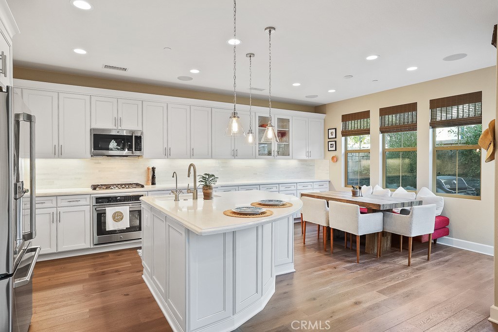 89 Lavender Lake Forest, CA 92630 - Photo 14 of 45 a kitchen with stainless steel appliances granite countertop a stove top oven a sink dishwasher a dining table and chairs with wooden floor