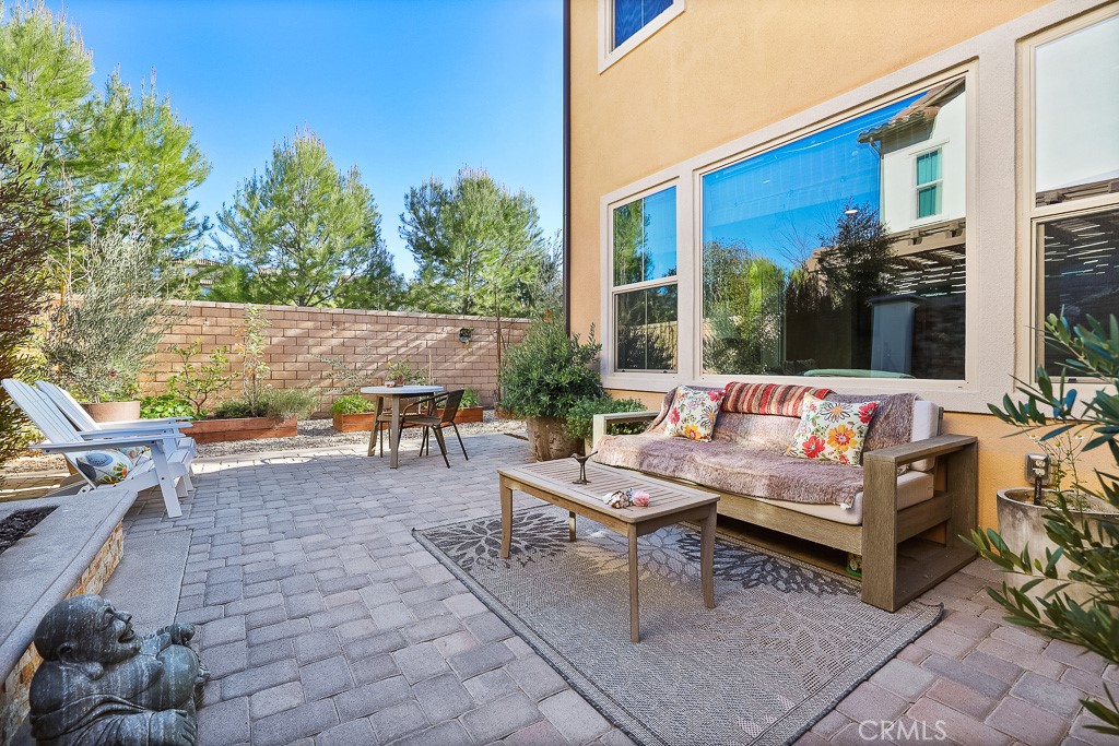 89 Lavender Lake Forest, CA 92630 - Photo 39 of 45 a view of a patio with couches and a table and chairs with floor to ceiling window plants and trees
