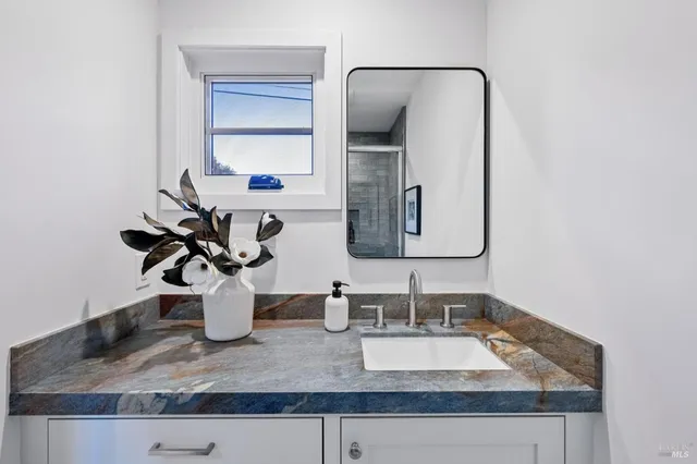 a bathroom with a granite countertop sink and a mirror
