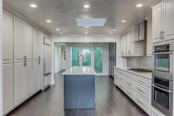 a large kitchen with stainless steel appliances granite countertop a large window and a refrigerator