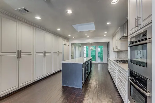 a large kitchen with stainless steel appliances granite countertop a large counter top a sink and a refrigerator