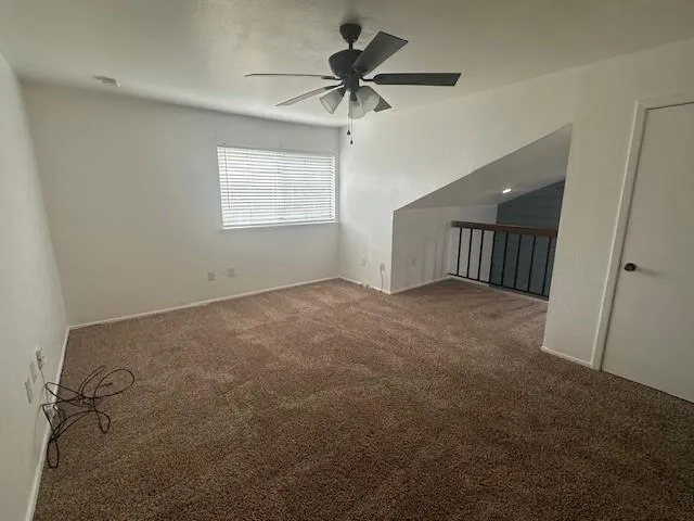 an empty room with a window and a fan