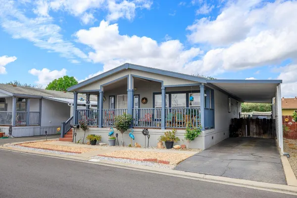 a front view of a house with a yard potted plants and wooden fence
