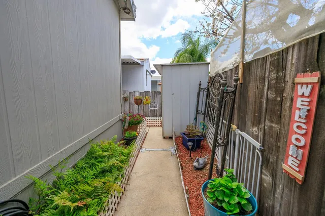 a view of a pathway of a house with a backyard and a patio