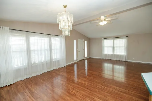a view of empty room with wooden floor and fan