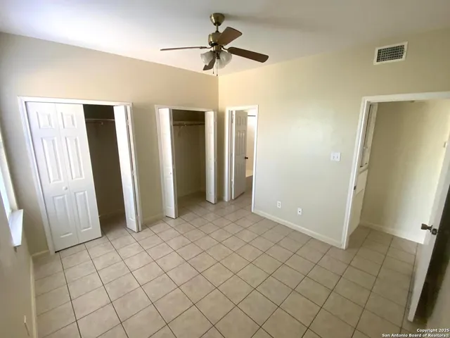 a view of an empty room and chandelier fan