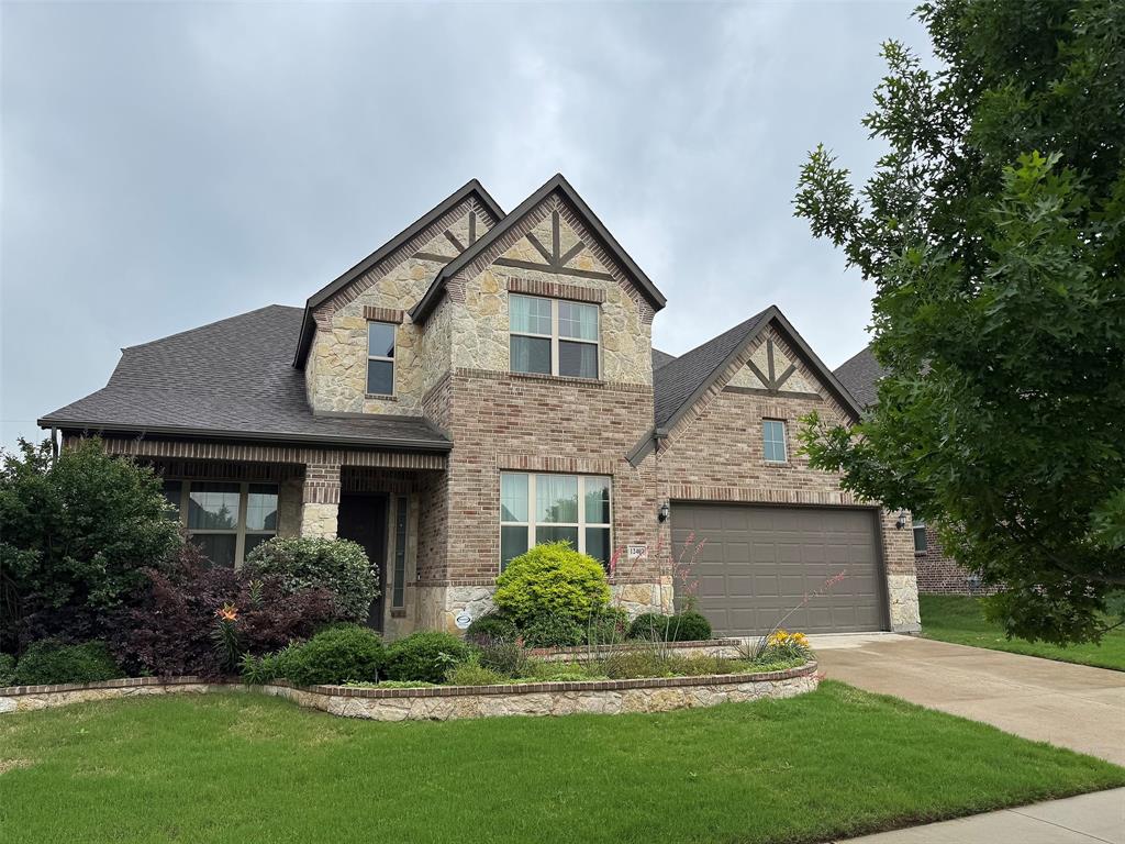12407 Scottswood Road Frisco, TX 75035 - Photo 2 of 14 Tudor house with stone siding, a front lawn, brick siding, concrete driveway, and roof with shingles
