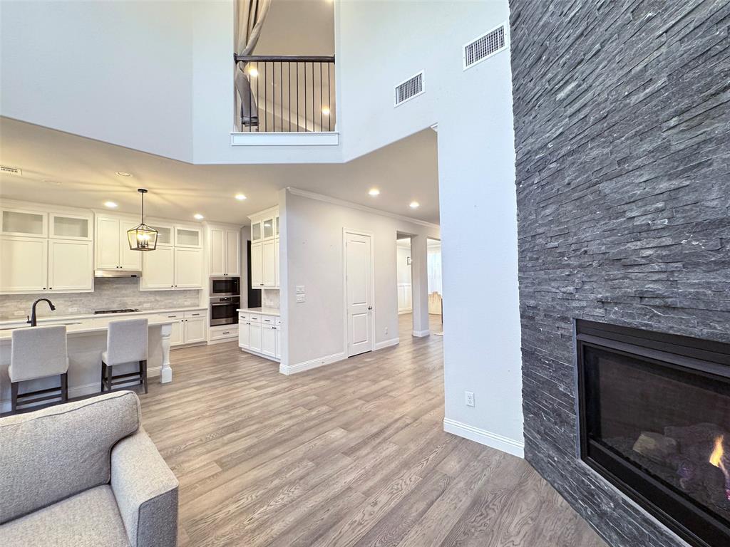 12407 Scottswood Road Frisco, TX 75035 - Photo 3 of 14 Living room with a fireplace, light wood finished floors, a high ceiling, and recessed lighting
