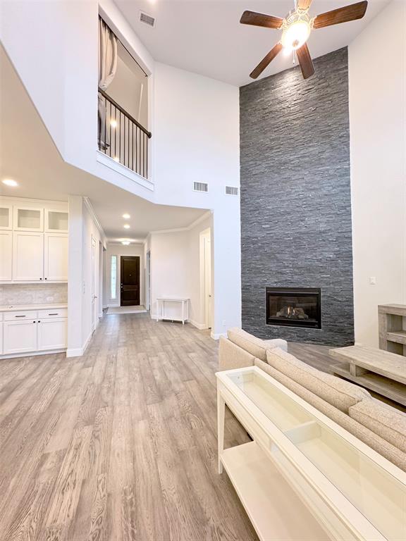 12407 Scottswood Road Frisco, TX 75035 - Photo 4 of 14 Unfurnished living room with a high ceiling, a large fireplace, light wood-style floors, a ceiling fan, and recessed lighting