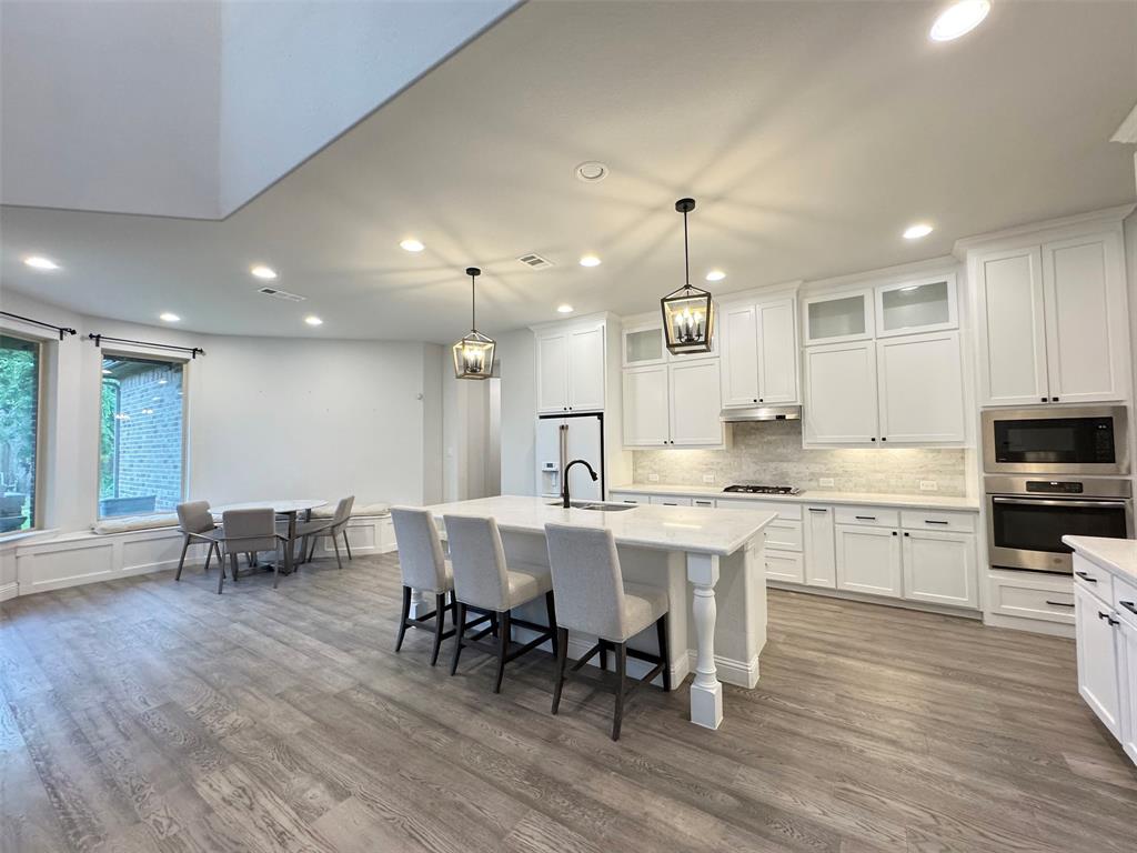 12407 Scottswood Road Frisco, TX 75035 - Photo 8 of 14 Kitchen with white cabinets, stainless steel appliances, glass fronted cabinets, and tasteful backsplash