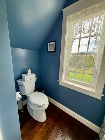 a white toilet sitting next to a window in a bathroom