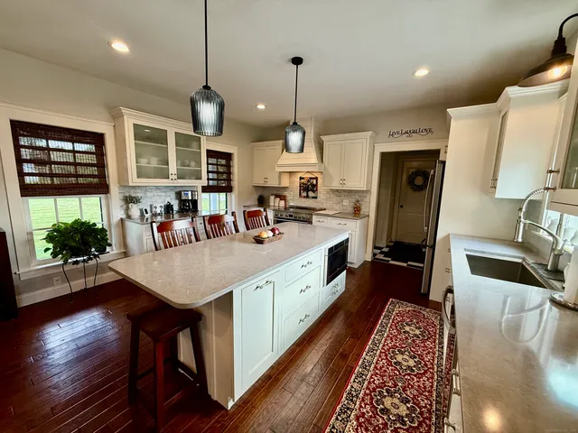 a large kitchen with stainless steel appliances granite countertop a stove a sink a refrigerator and a dining table with wooden floor