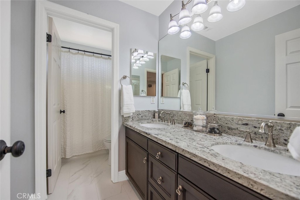 30177 Sagecrest Way Castaic, CA 91384 - Photo 35 of 54 a bathroom with a granite countertop sink a large mirror and a shower
