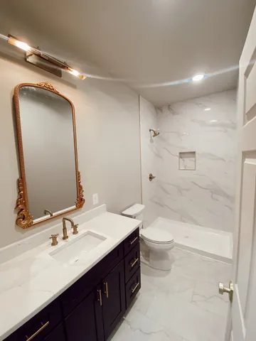 a bathroom with a double vanity sink toilet mirror and shower