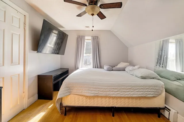 a bedroom with a bed a window and painting on the wall