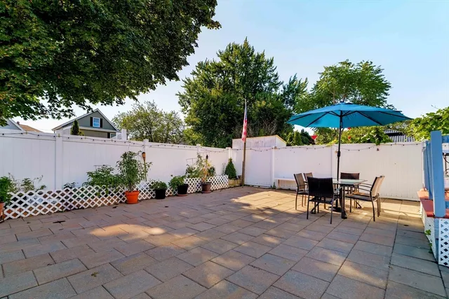 a view of a backyard with chairs under an umbrella