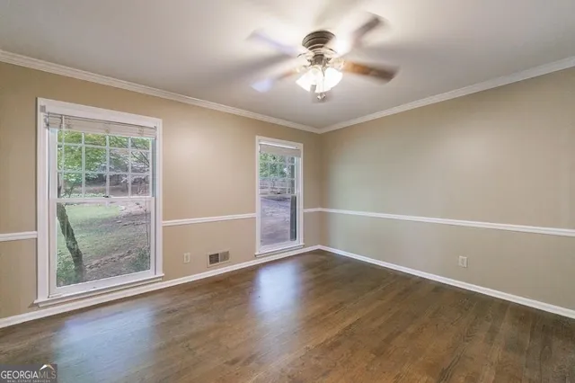 a view of an empty room with wooden floor fireplace and a window