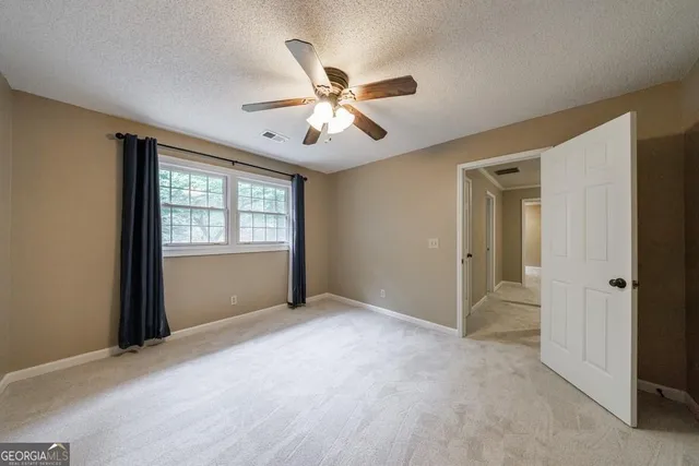 an empty room with windows and chandelier fan