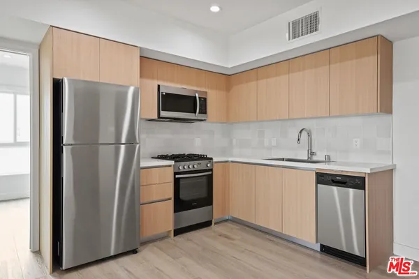a kitchen with stainless steel appliances granite countertop a refrigerator stove top oven and sink