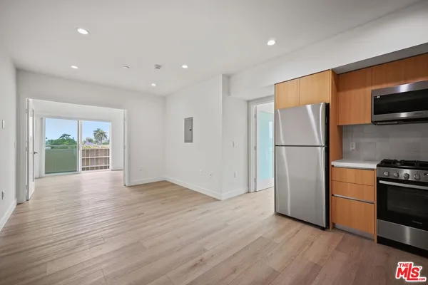 a view of kitchen with stainless steel appliances wooden floor and living room