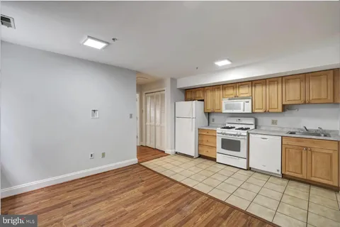 a kitchen with stainless steel appliances granite countertop a stove top oven a sink dishwasher and a refrigerator with wooden floor