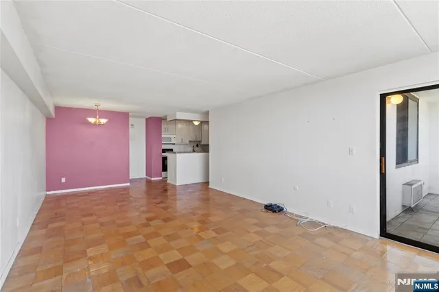 a view of an empty room with a window and a kitchen