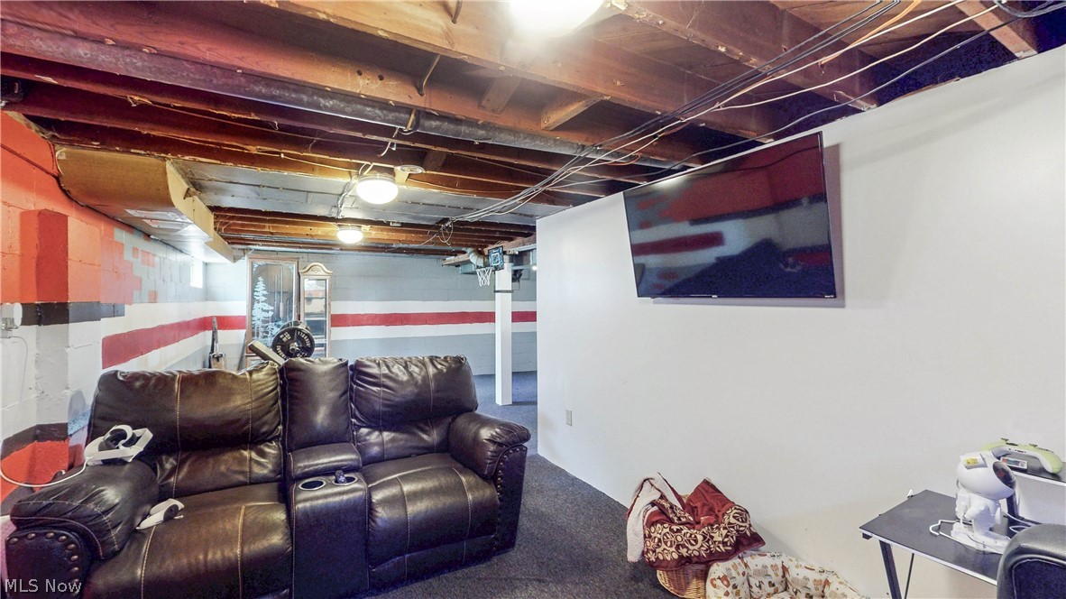 3659 Morrow Road Kent, OH 44240 - Photo 28 of 39 Recreation room featuring exposed wood ceiling joists and support beams, white painted walls, and dark carpeting