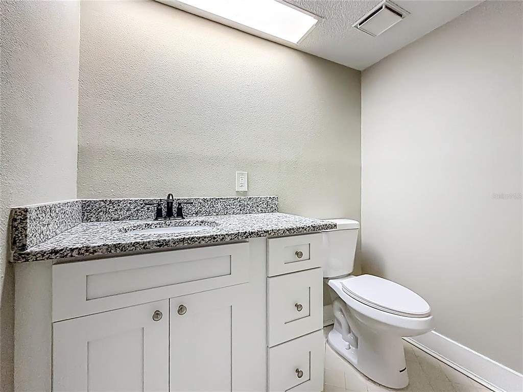 11603 West Bayshore Drive, Unit 118 Crystal River, FL 34429 - Photo 28 of 73 a bathroom with a granite countertop toilet and a sink