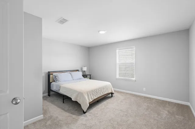 a bed sitting in a spacious bedroom next to a window
