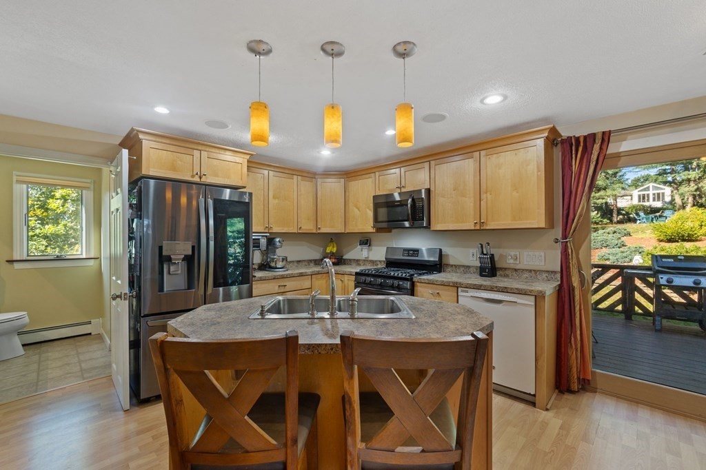 70 Colvintown Road Coventry, RI 02816 - Photo 5 of 41 a kitchen with stainless steel appliances granite countertop a stove top oven a refrigerator a sink dishwasher and a dining table with wooden floor