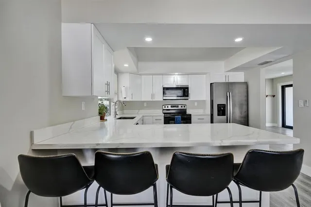 a kitchen with stainless steel appliances a dining table chairs microwave and sink