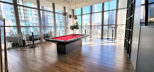 a living room with furniture a large window and wooden floor