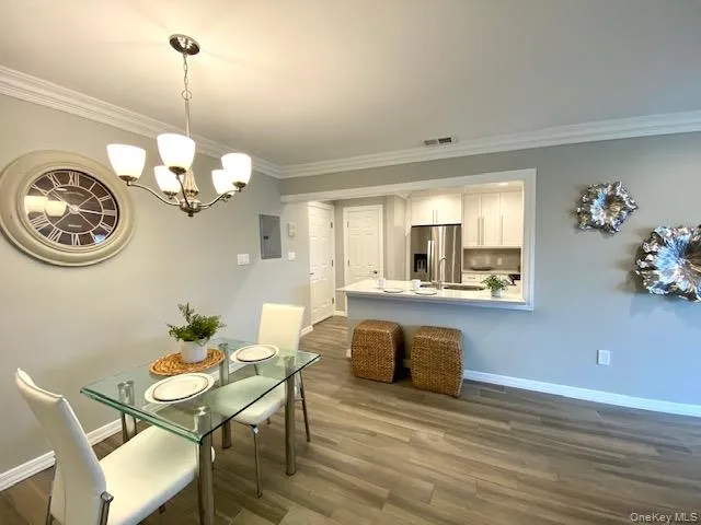 a view of a dining room and livingroom with furniture wooden floor a chandelier