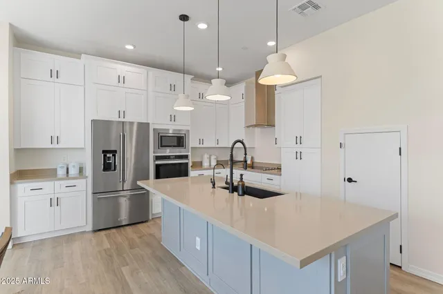 a kitchen with stainless steel appliances granite countertop a sink a center island a refrigerator and a stove