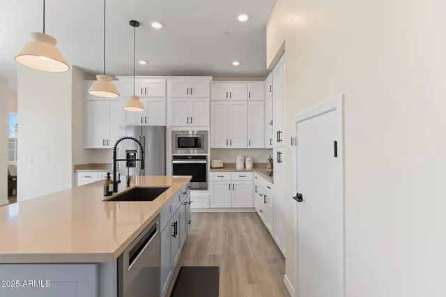 a kitchen with stainless steel appliances a sink a stove a refrigerator a center island and cabinets