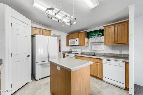 a kitchen with stainless steel appliances granite countertop a refrigerator a sink dishwasher a stove top oven a refrigerator with island and cabinets