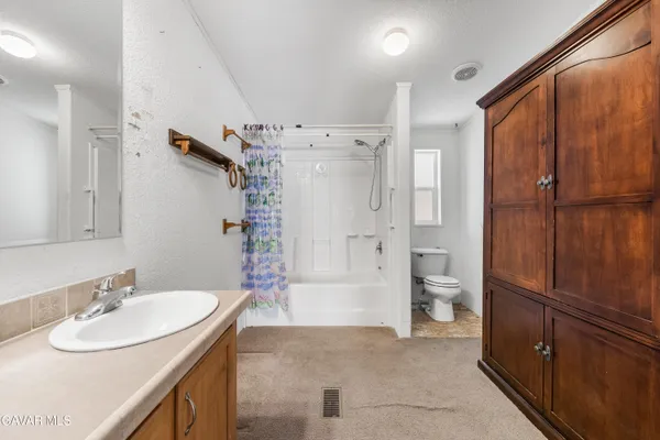 a bathroom with a granite countertop toilet sink and mirror