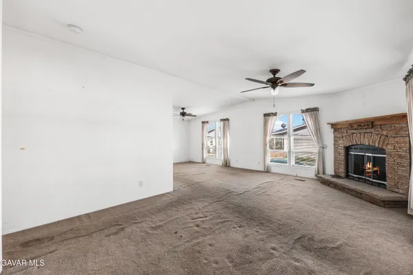 a view of a livingroom with a fireplace and a ceiling fan