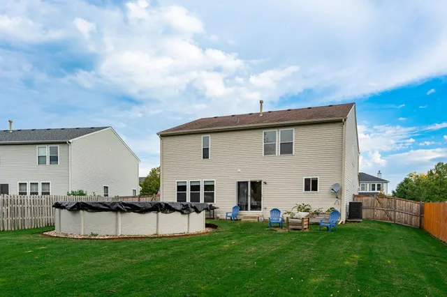 a view of a white house in front of a big yard with potted plants